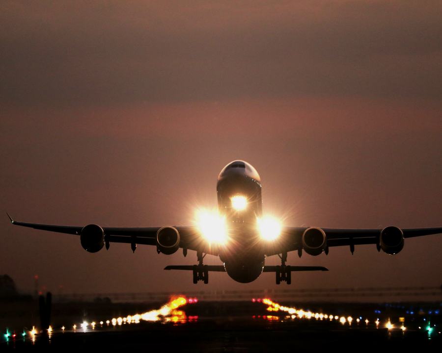 Four-engine jet taking off at dusk with its landing lights on
