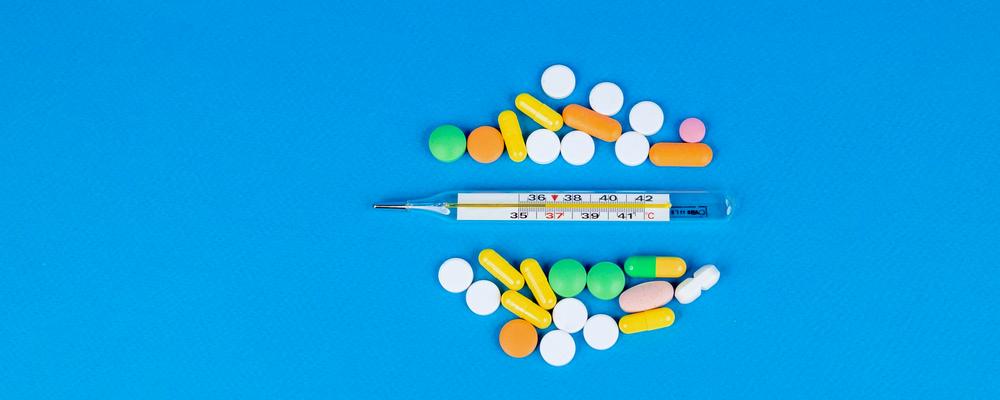 Thermometer and tablets on a blue background